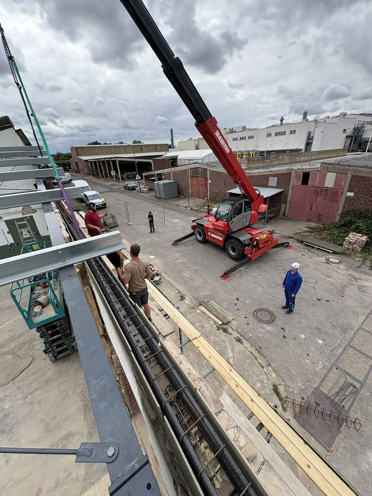 Blick von oben auf eine Baustelle mit Teleskoplader, Stahlträgern und Bewehrung